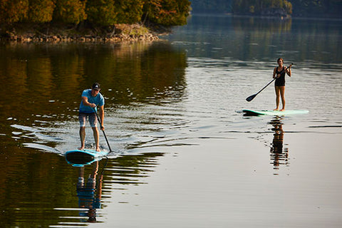 A SUP user paddling a planing hull paddle board