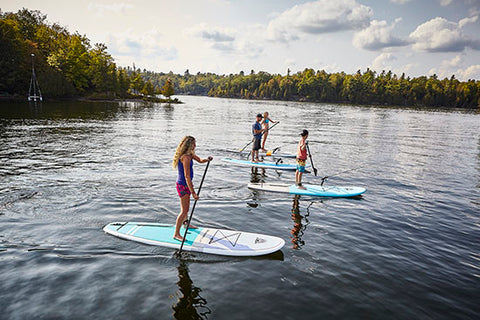 a family enjoying stand up paddle boarding on a lake